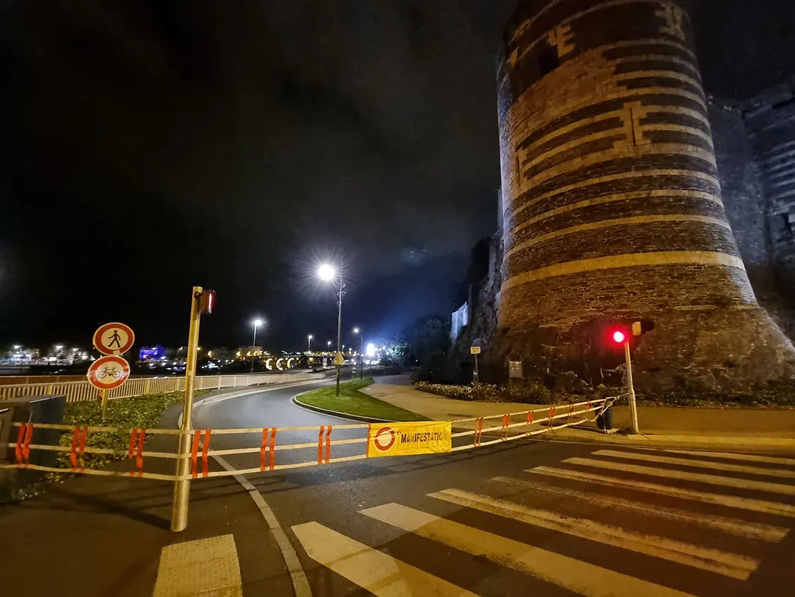Barrière textile MANIFESTATION fermant la voie au pied du château d'Angers, de nuit