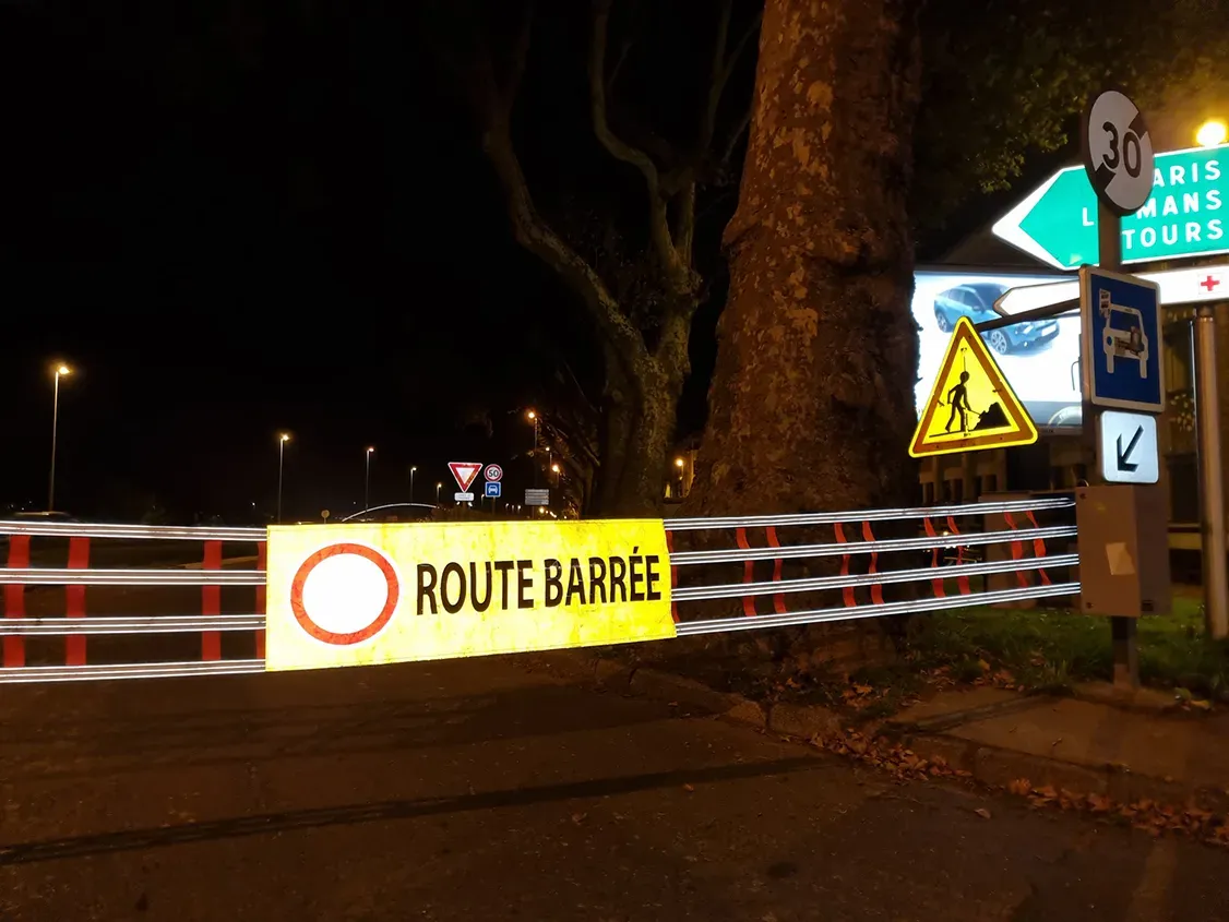 Bannière ROUTE BARRÉE rétro-réfléchissante illuminée de nuit dans les phares